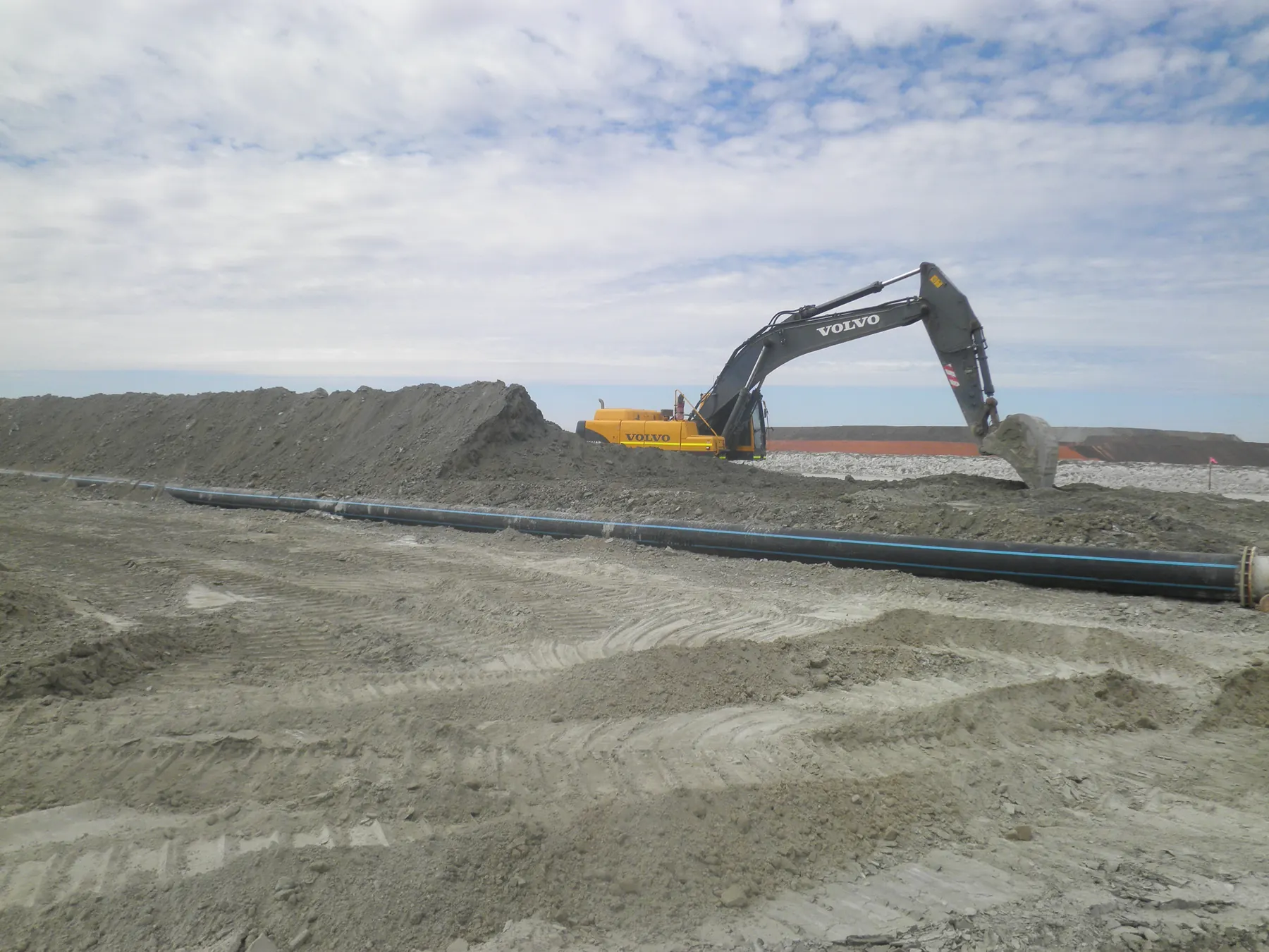 Excavator working beside a pipeline on an earthworks site